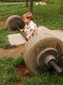 little boy try lift up the barbell in the park
